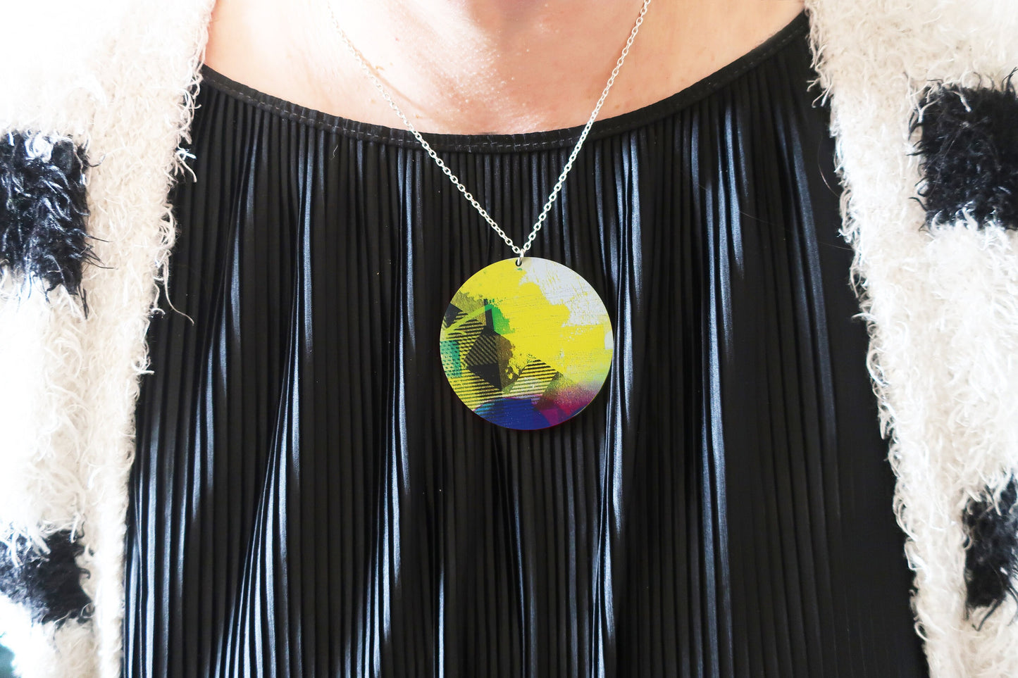 Person wearing a colorful pendant necklace with a black outfit