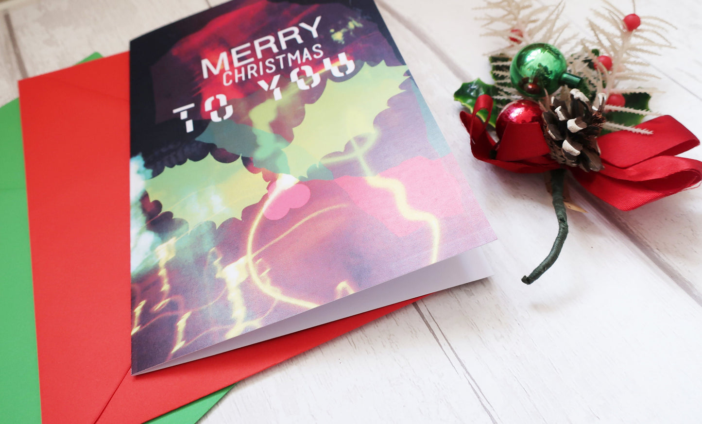 Colorful Christmas card with 'Merry Christmas to You' text on a white surface with red and green envelopes.