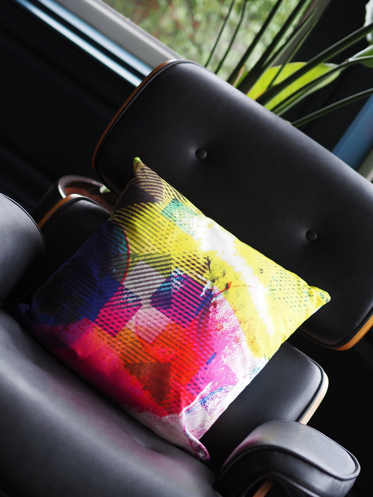 Colorful pillow on a seat with a blurred plant in the background