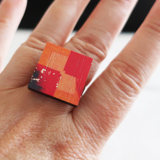 Hand wearing a ring with a geometric design on a neutral background