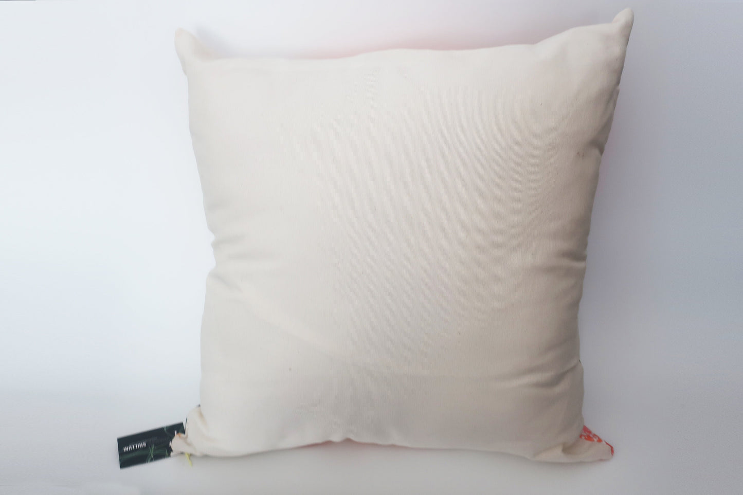 Beige pillow with a brand tag on a white background