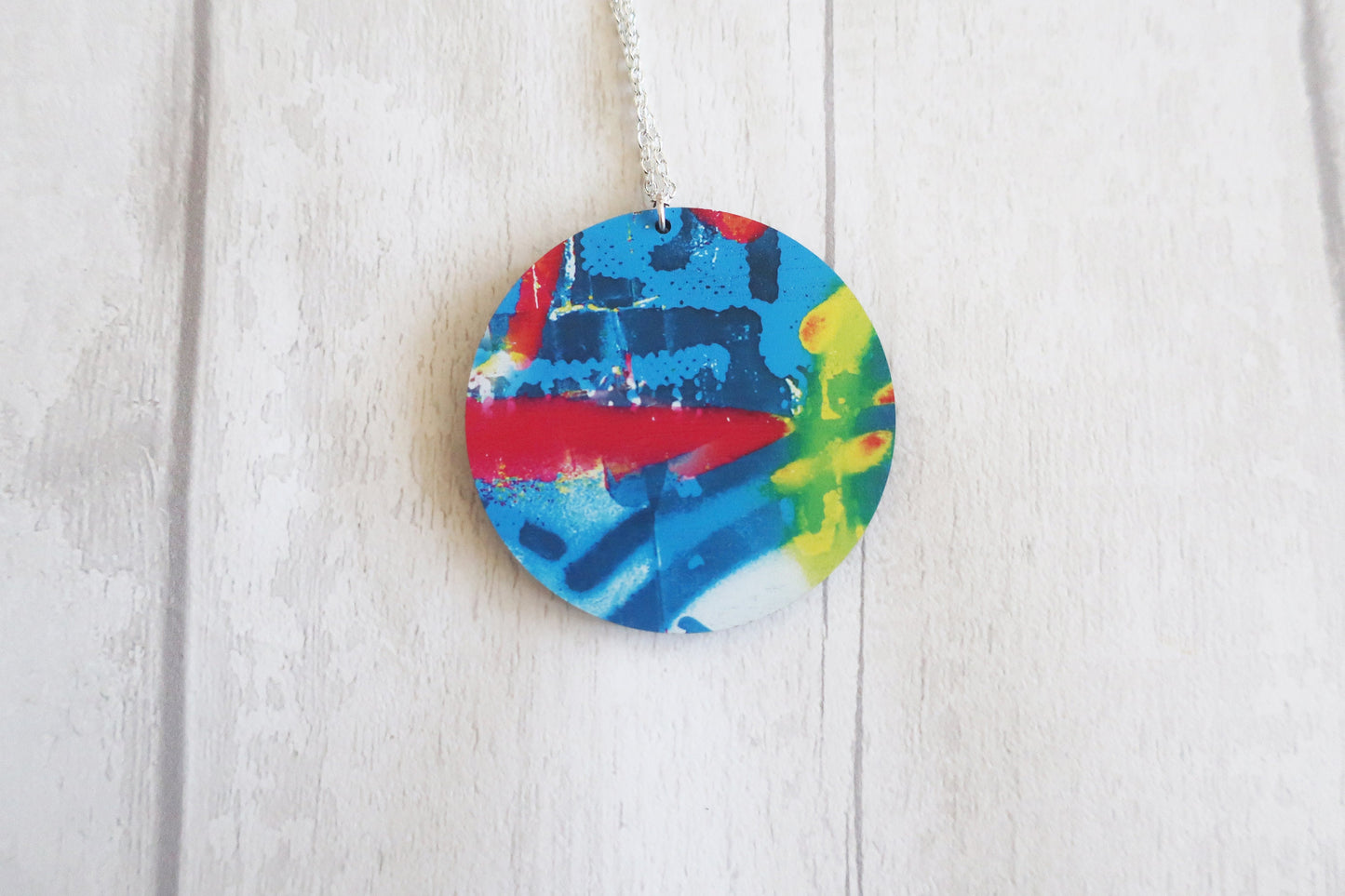 Colorful round pendant on a white wooden background