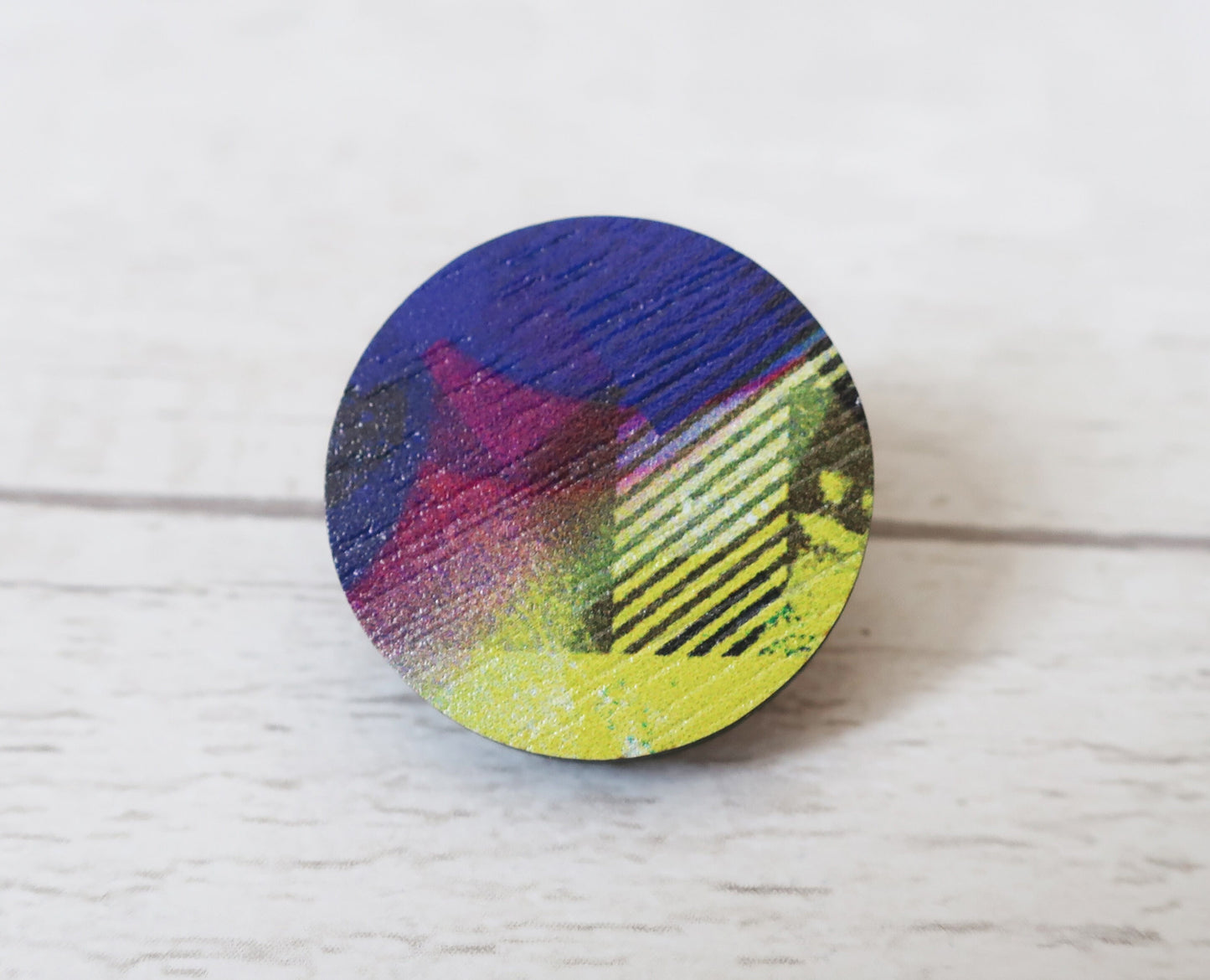 Round colorful pin badge on a light wooden surface