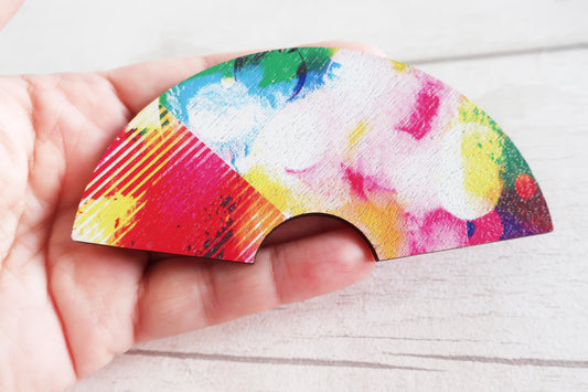Colorful hairclip held by a hand on a white surface