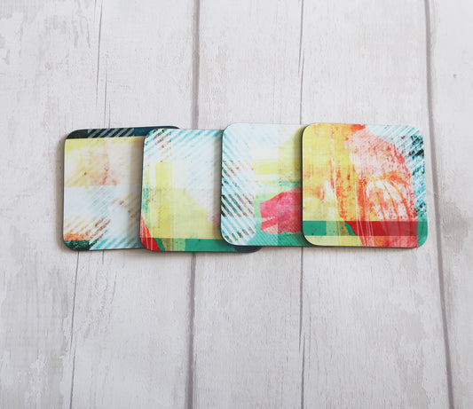 Four colorful coasters on a light wooden surface