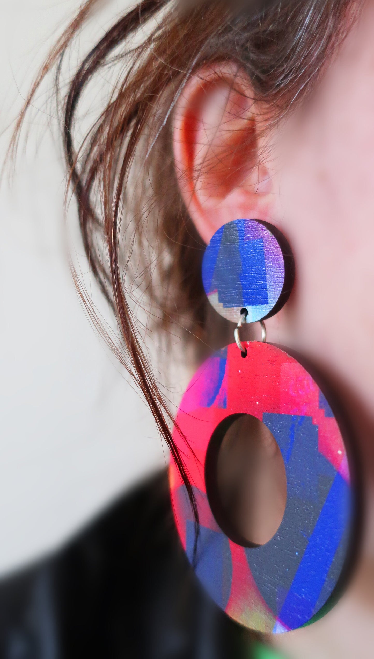 Close-up of colorful circular earrings worn by a person.