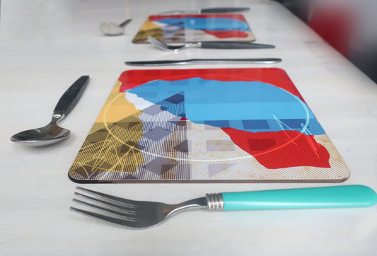 Colorful placemats with geometric designs on a white table with cutlery.