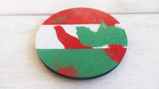 Round wooden brooch with red and green abstract design on a white surface