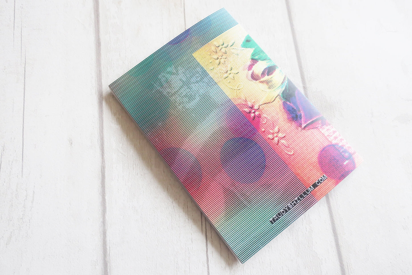 Colorful card with embossed designs on a white wooden surface