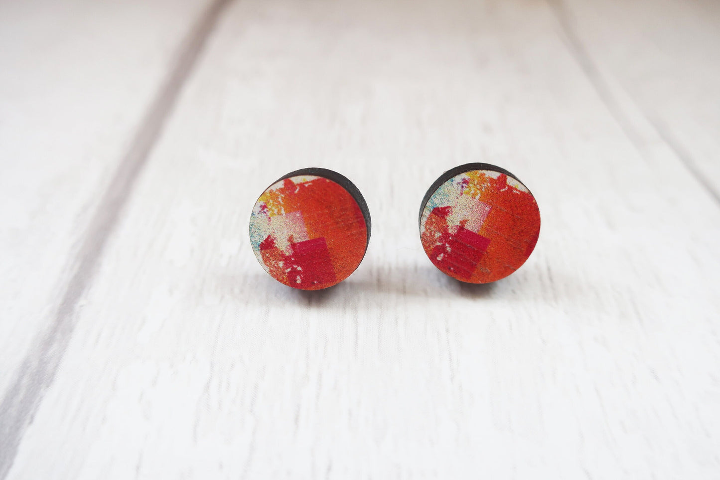 Pair of round earrings with colorful design on a white background