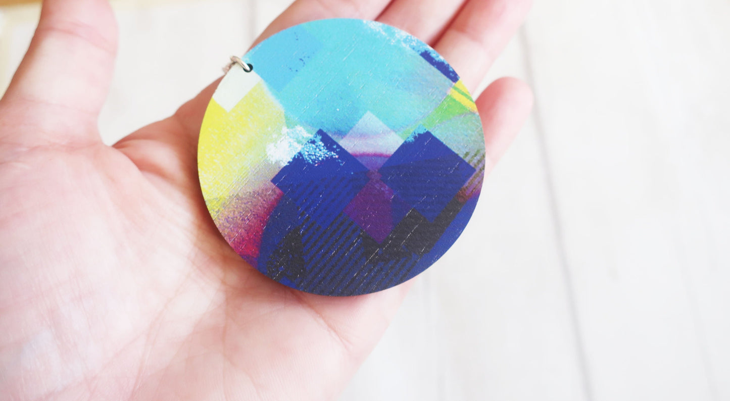 Colorful pendant held in a hand against a white background