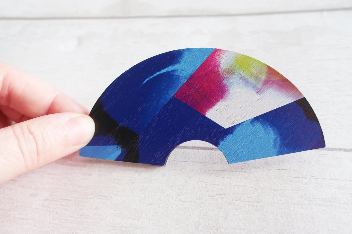 Color fan shaped hairlip by a hand on a light wooden surface