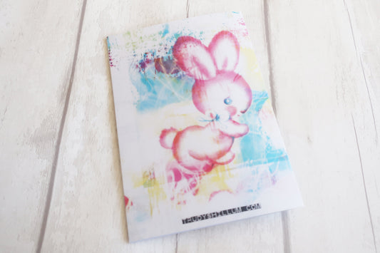 Greeting card with a colorful bunny illustration on a light wooden surface