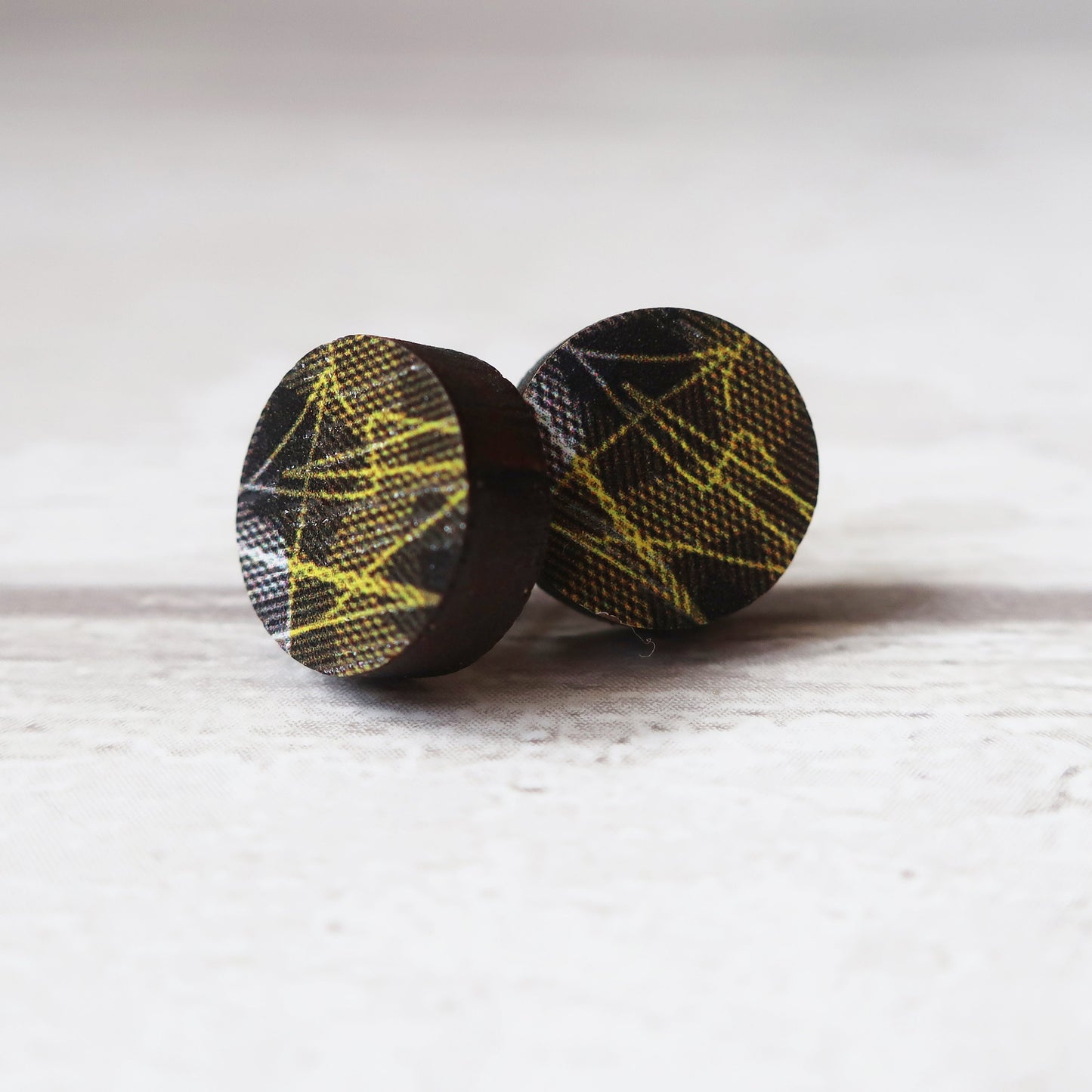 Pair of round earrings with black and yellow pattern on a white background