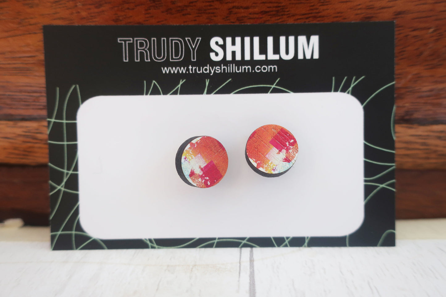 Round earrings with a floral pattern on a Trudy Shillum branded card.