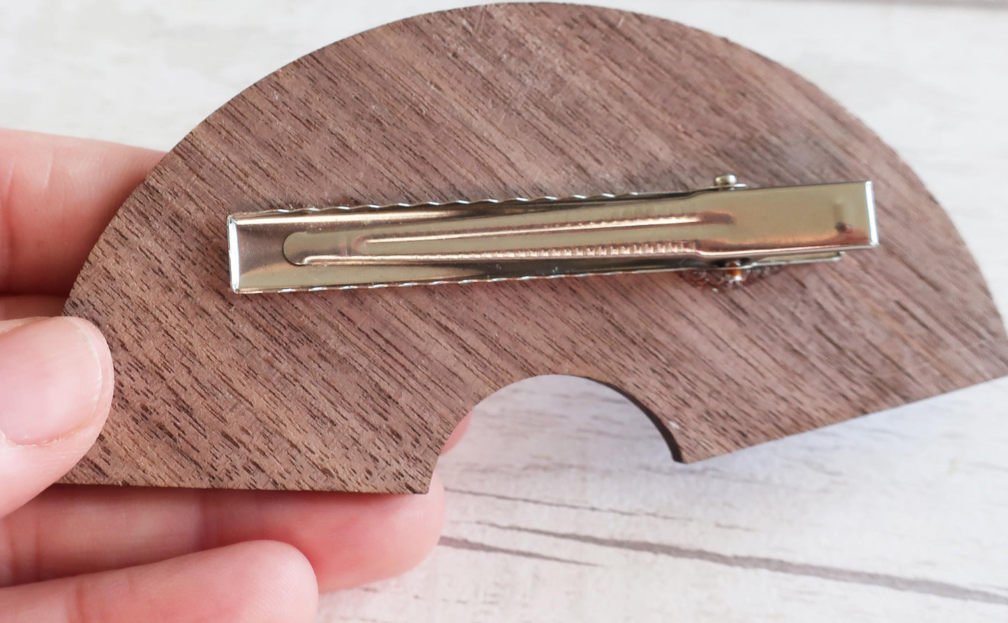 Gold clip on a wooden hairclip held by a hand