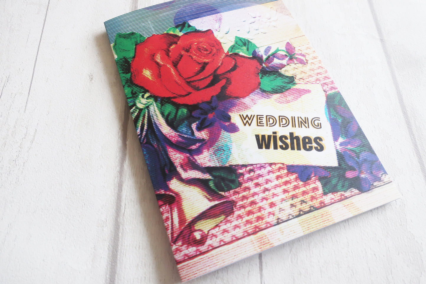 Greeting card with floral design and 'Wedding Wishes' text on a white surface