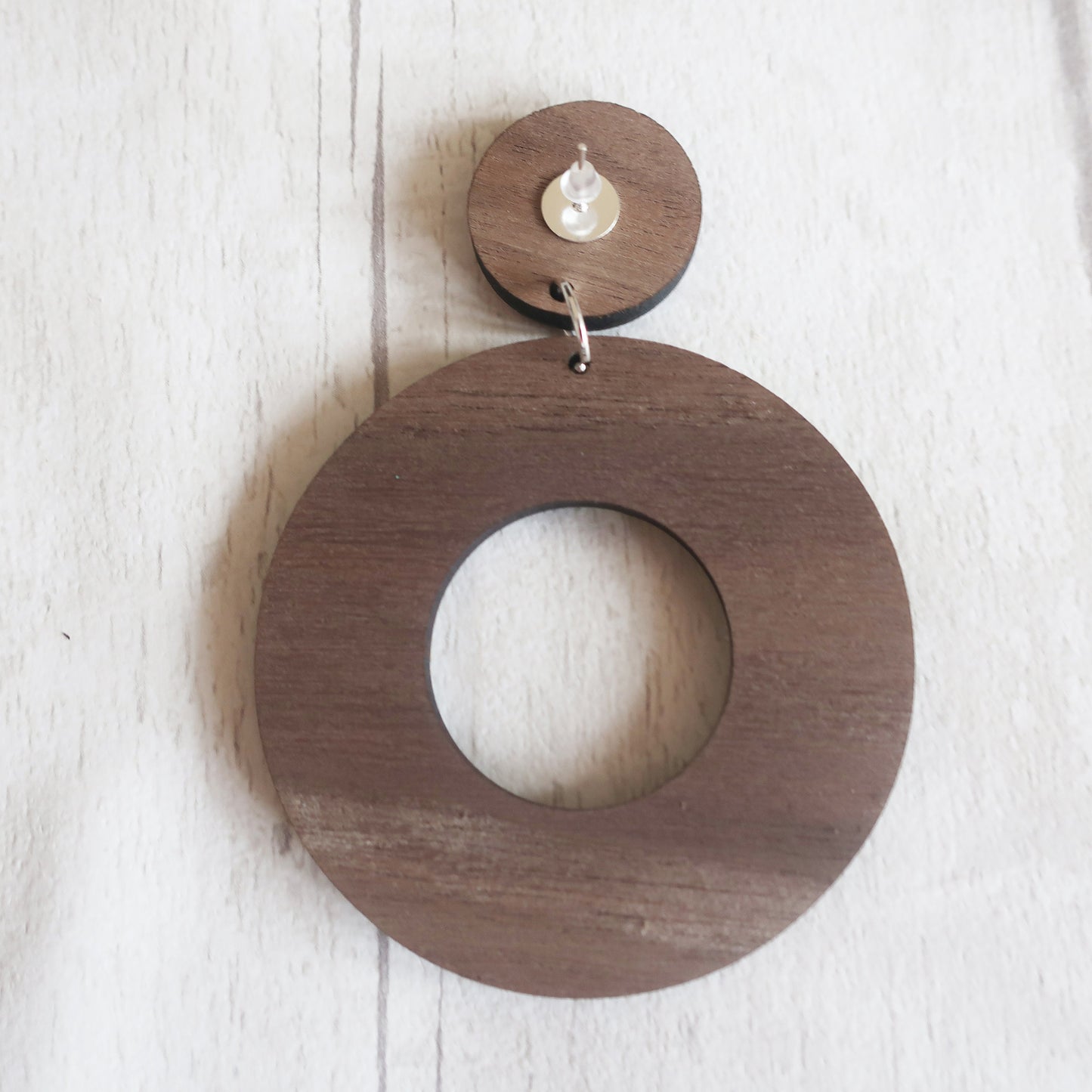 Wooden circular earring with a smaller circle cutout on a light wooden background