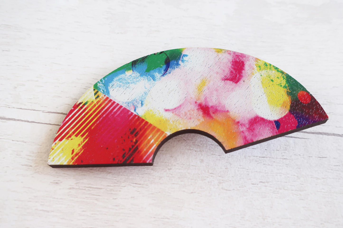 Colorful abstract hairclip on a white wooden surface