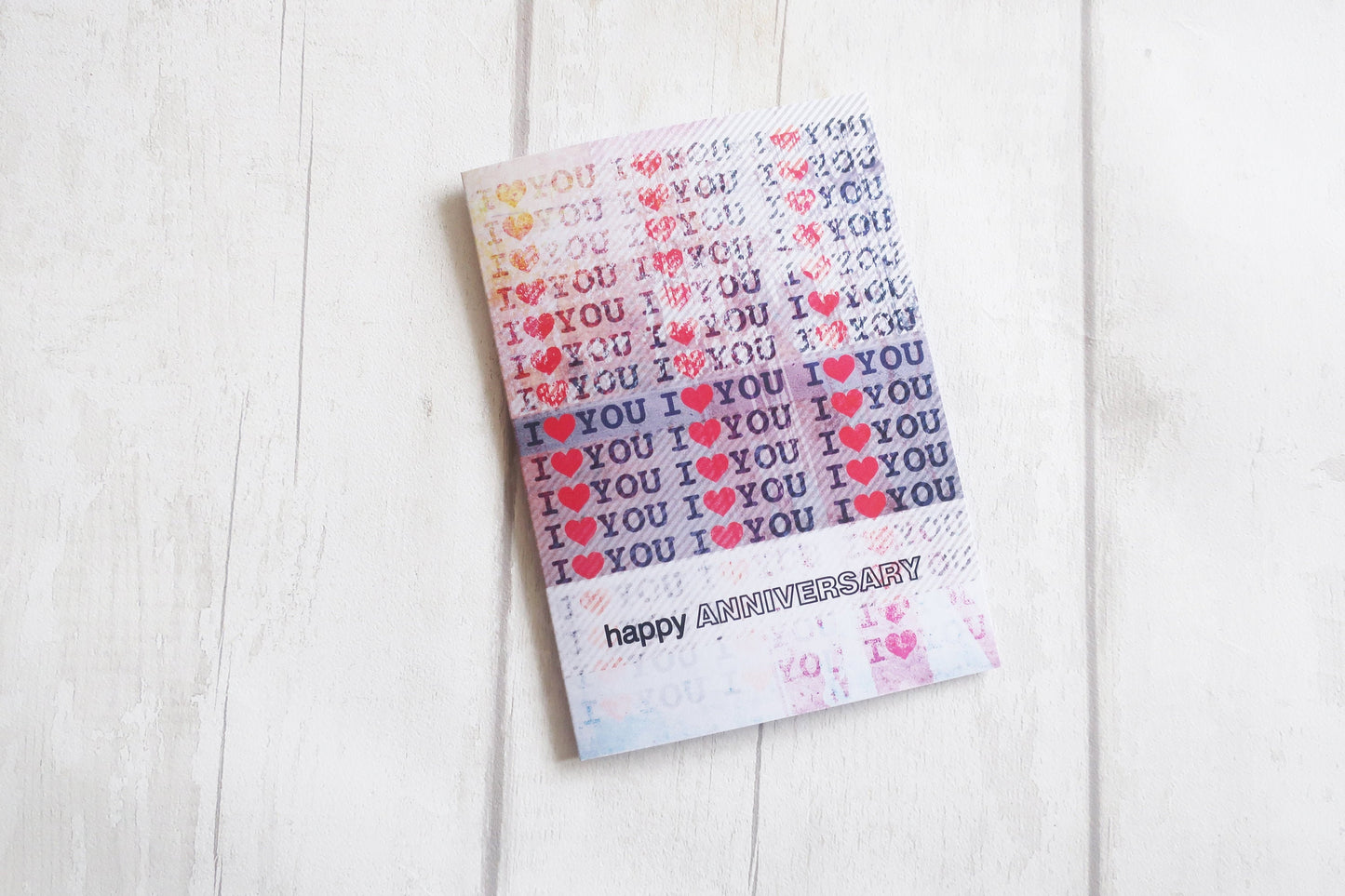 Card with 'I love you' text pattern on a white wooden surface