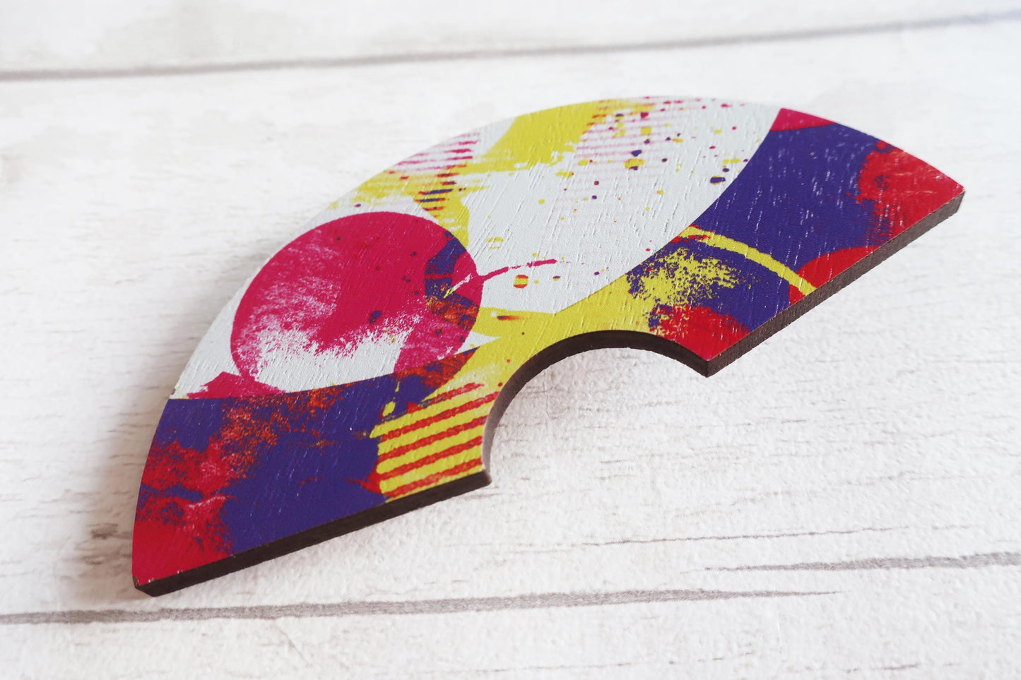 Colorful abstract design hairclip on a wooden surface