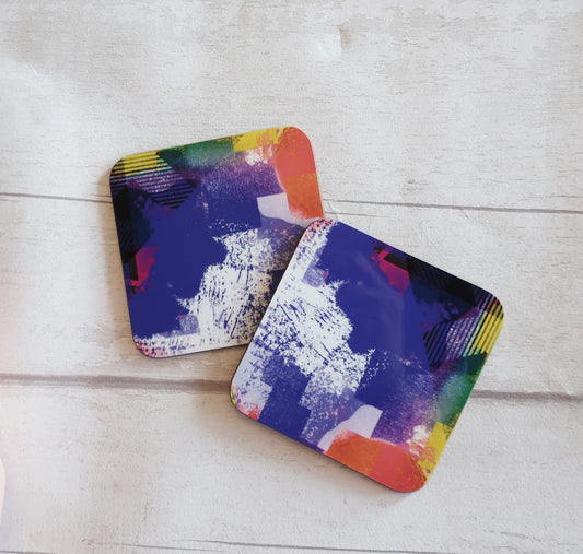 Two colorful coasters with abstract patterns on a light wooden surface