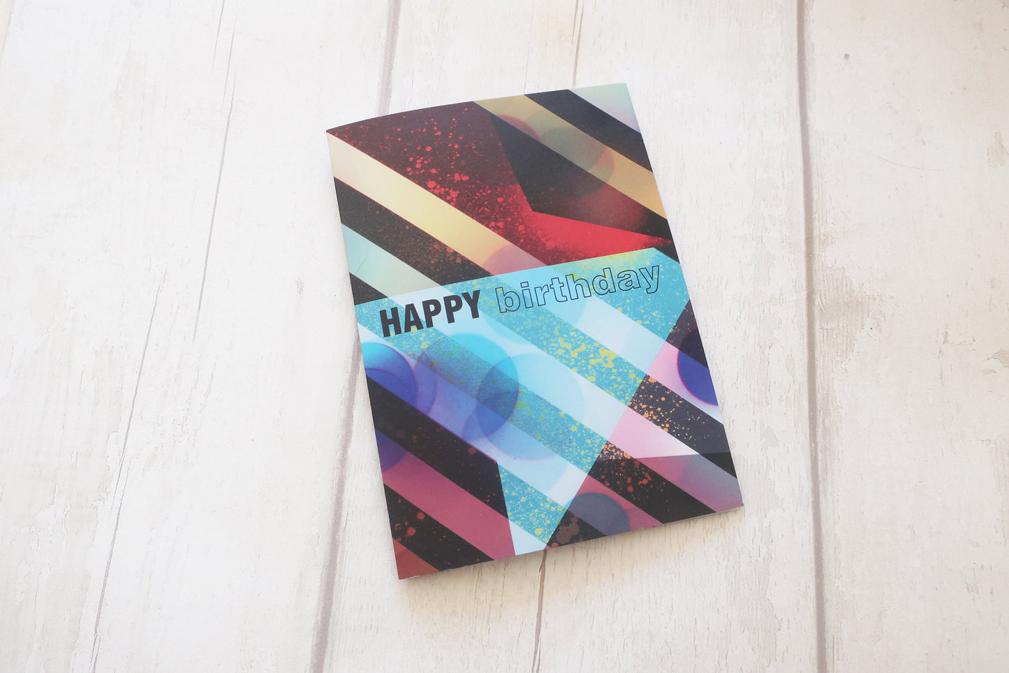 Colorful birthday card with geometric design on a white wooden surface