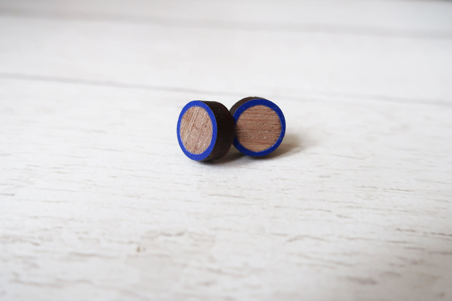 Wooden earrings with blue accents on a light wooden surface