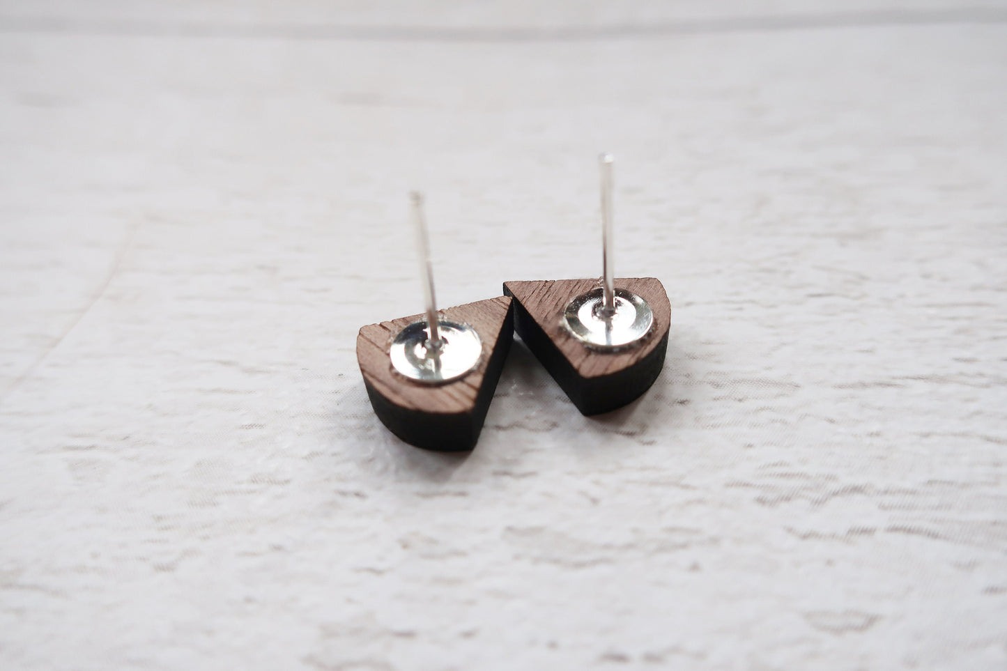 Wooden earrings with metal components on a light wooden surface