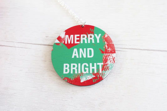 Round Christmas necklace with 'Merry and Bright' text on a white wooden surface