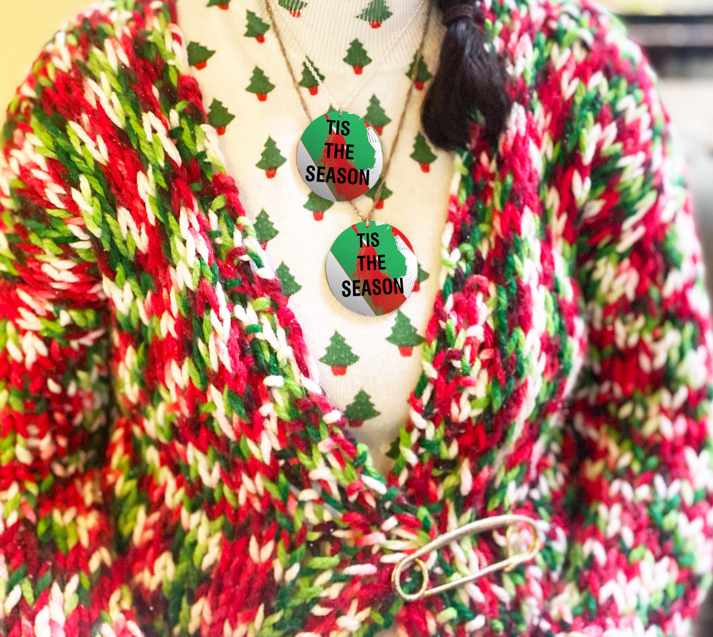 Red, green, and white striped cardigan with 'Tis the Season' necklaces on a mannequin.