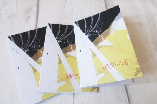 Three notebooks with black and white designs on a light wooden surface