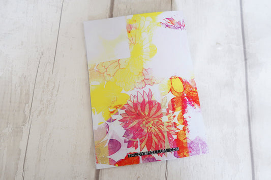 Floral card with yellow and pink flowers on a light wooden surface