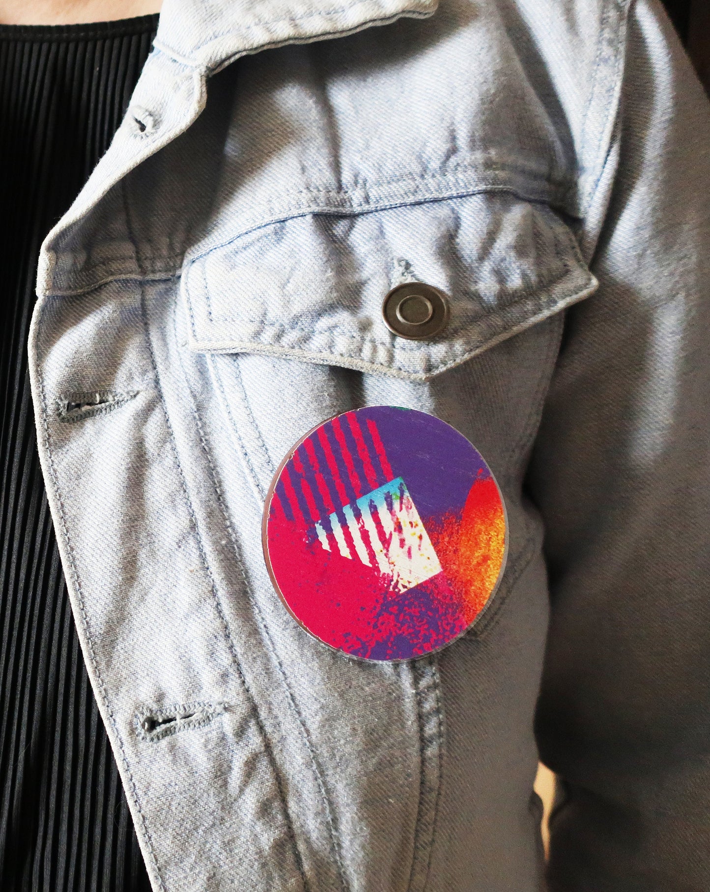 Colorful round brooch on a denim jacket