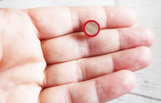 Small red circular earring on a person's palm