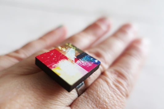 Colorful square ring on a person's finger with a white background