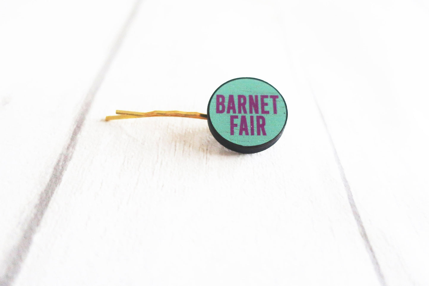 Green hair clip with 'Barnet Fair' text on a white background