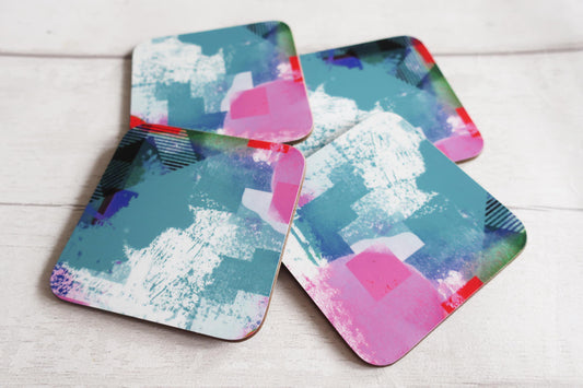 Set of four colorful abstract coasters on a light wooden surface