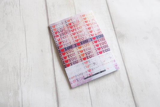 Greetings card with 'I love you' pattern on a light wooden surface