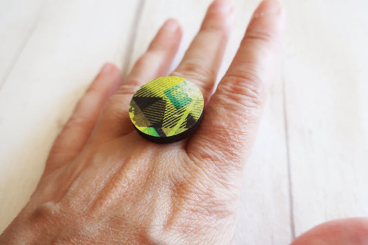 Hand wearing a ring with a green and black pattern on a white background