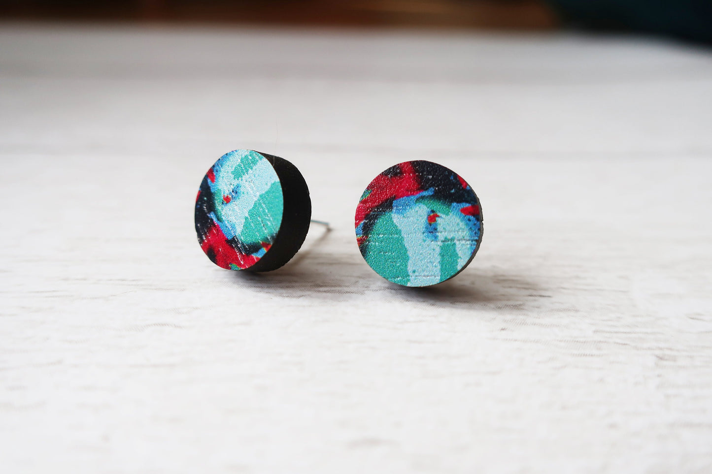 Colorful round earrings on a light wooden surface