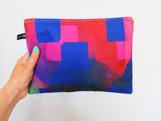 Colorful pouch with geometric pattern held by a hand on a white background
