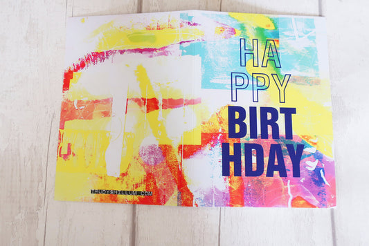 Colorful birthday card with 'Happy Birthday' text on a wooden surface