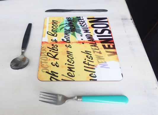 Colorful placemat with text on a white surface with cutlery.