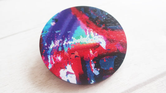 Colorful circular brooch with a abstract design on a white surface