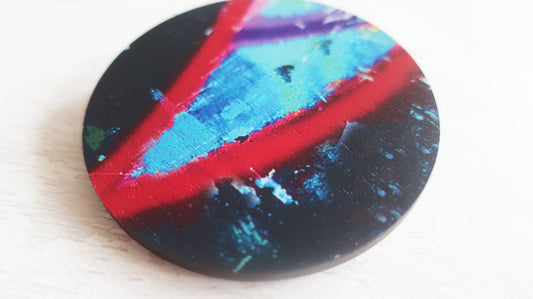 Round brooch with blue and red design on a white background