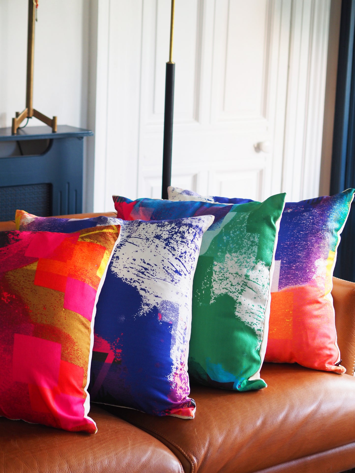 Colorful abstract-patterned pillows on a brown sofa with a blurred background