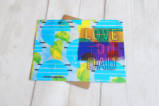 Colorful card with 'Love You Dad' text on a wooden surface