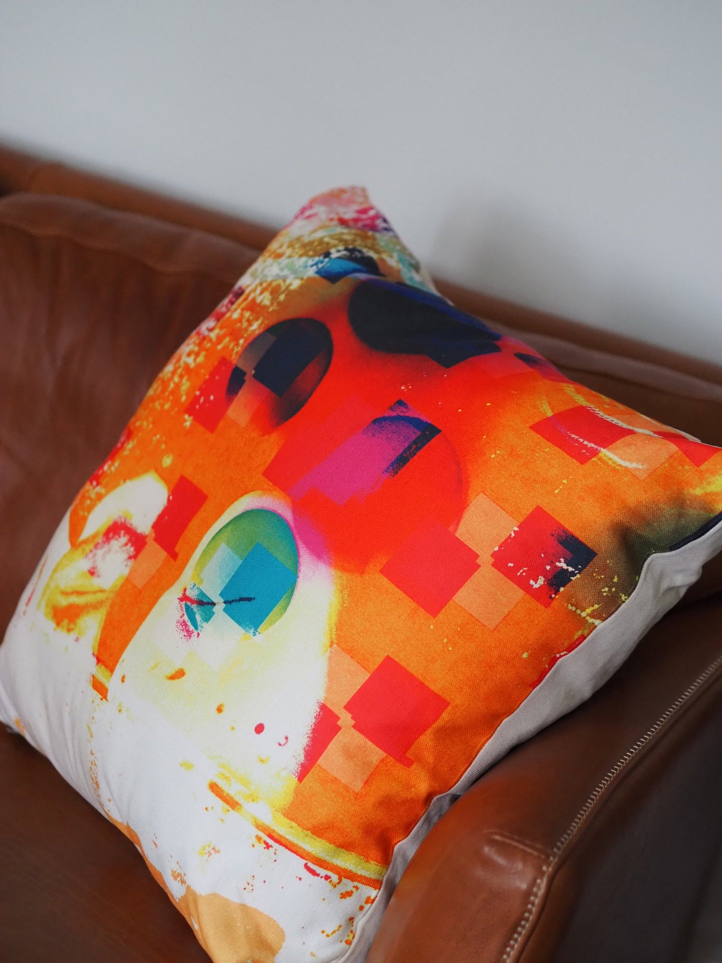Colorful pillow with abstract design on a brown leather couch