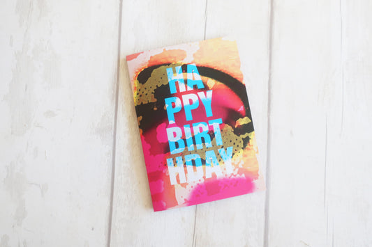 Colorful birthday card with 'Happy Birthday' text on a white wooden surface